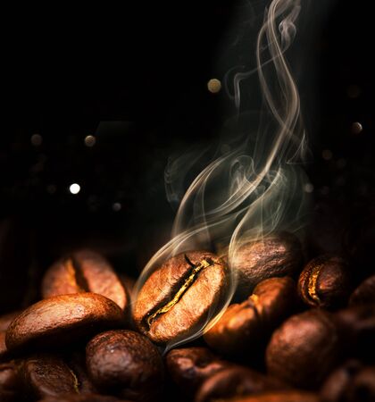 Roasted coffee beans. Seeds of freshly roasted coffee with smoke. Coffee beans closeup with emphasis on the grain with smoke.の写真素材