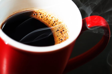 Fragrant black coffee in a cup. Smoke from black hot coffee. Advertising coffee.