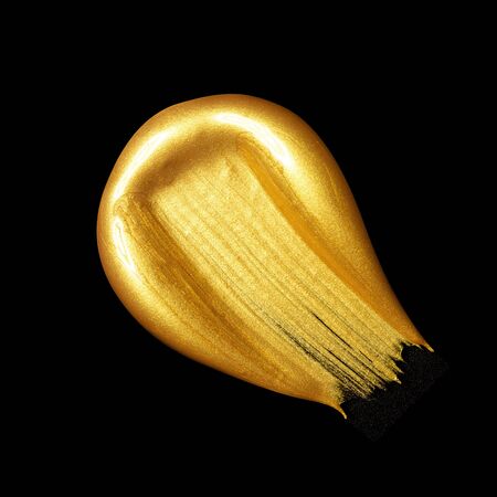 Creative brushstrokes of gold paint isolated on a blackの写真素材