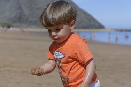 Little kid in the beach playing with red bucket  Tenerifeの写真素材