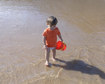 Little kid in the beach playing with red bucket  Tenerifeの写真素材