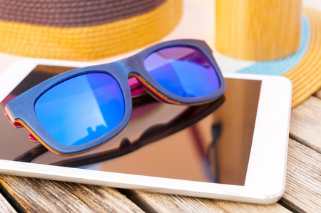 Wooden colorful sunglasses, tablet and hat. Beach fashion styleの写真素材