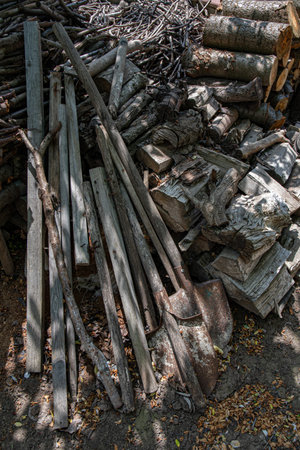 Heap of old rusty metal shovels and pile of weathered firewood. Rough wooden textures. Rustic...