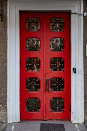 Retro style wooden doorway. Ornate red double door with rows of square shape windows and patterned...