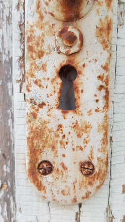 Old door details with rusty metal keyhole closeup on distressed wood background with copy space....