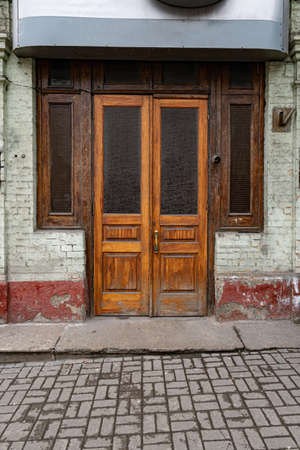 Kiev / Ukraine - 02 22 2020: Facade of historic building with old wooden door and dark windows by sides. Architecture of European city. Retro building exteriorのeditorial素材