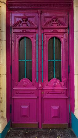 Baroque antique wooden door panels painted in vibrant pink purple color with ornate frames and arch windows. Heritage of historic building in European city Odessa of Ukraineの写真素材