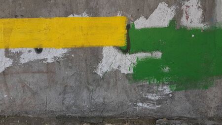 Old rough cement wall with rectangle stains of yellow and green stains. Abstract background of construction repair industryの写真素材
