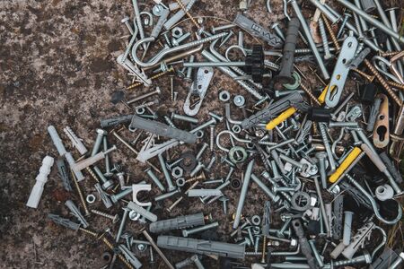 Flat lay of steel bolts and nuts, hooks and dowels on grunge stone background with copy space. Soft focus to grunge metal fastener fittings. Industrial backdrop for Fathers Dayの写真素材