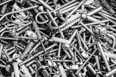 Pile of many assorted metalware bolts and nuts. Black and white photo of work tools closeup. Abstract industrial background for Fathers Dayの写真素材