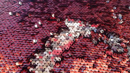 Shining round sequins texture. Red and silver two-sided sequins fabric surface closeup. Glitter texture. Fashion glamour style. Textured scales of sparkling sequinsの写真素材