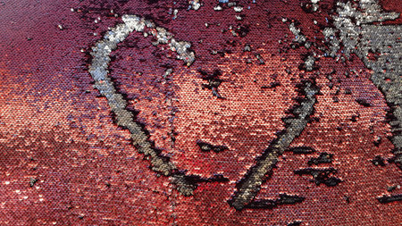 Heart silhouette on sequin fabric. Red and silver two-sided sequins background. Shiny glitter texture. Fashion glamorous textured scales. Love concept. Valentine's Day decorの写真素材