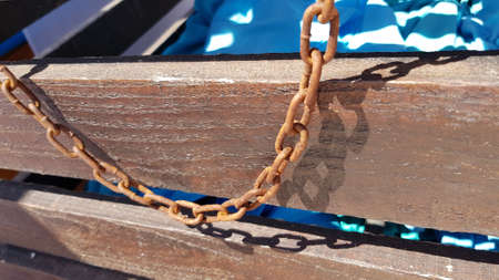 Vintage rusty metal chain hanging from wooden treasure chest. Fake pirate chest decoration detailsの写真素材