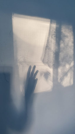 Female hand shadow silhouette trying to reach the window. Depression concept.