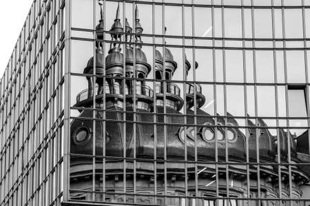 Reflection of chapel and bell tower in mirrored wall. Distorted reflection in glass panoramic windows. Black and white photo of corporate building exteriorの写真素材