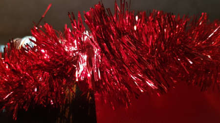 Defocused shiny silver red tinsel sparkling in bright light. Winter holiday background with blurry tinsel textureの写真素材