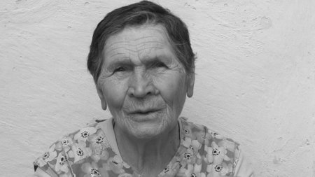 Black and white authentic portrait of 80 years old lady of mixed ethnicity. Wrinkled face of elderly woman with concerned emotion and suspicious sight. Senior people real lifeの写真素材