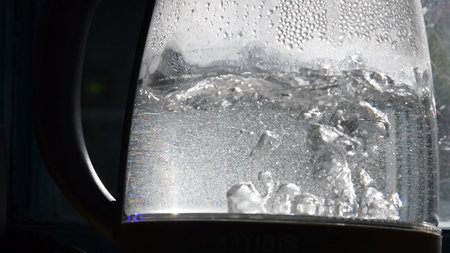 Defocused bubbles in hot water boiling inside glass teapot in bright sunlight. Closeup of boiling...