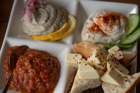 Closeup of butter pieces with spicy seasonings. White crockery plate with mezze tasting set of...