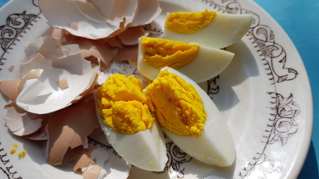 Top view hard boiled eggs sliced in quarter parts of triangle shape and broken eggshell on retro...