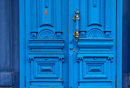 Ornate door handle with old double wood door painted in blue. Vintage wooden doorway. Classical architecture detailsの写真素材