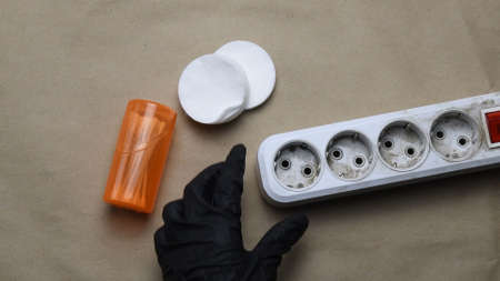 POV view of hand in black rubber glove tiuch dirty plastic extension socket. Cleaning and maintenance of electric extender equipmentの写真素材