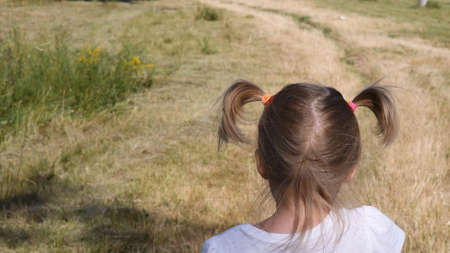 Toddler girl head with rural landscape background. Baby hair tied with colorful rubber bands in two funny ponytailsの写真素材
