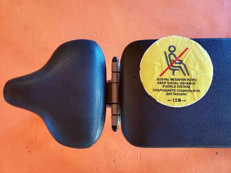 Yellow sticker warning about keeping social distance in Turkish, English, German, Russian languages. Social distancing caution sign on sport bench of gym equipment. Text - keep social distanceの写真素材