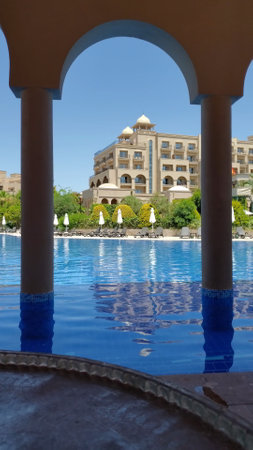 Summer resort with Arabic style buildings. Luxury vacation scene with nobody at pool rippled water. Vertical shot framed by arch of luxury resort Spice hotel spa. Belek, Turkey, 07 09 2021のeditorial素材