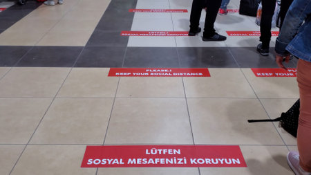 Red lines with social distance warning and feet of passengers at Antalya airport. International air travel during Covid-19 pandemic. Antalya, Turkey, 07 21 2021のeditorial素材