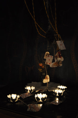 Romantic vintage still life with candles in darkness and playing cards of red hearts. Symbols of...