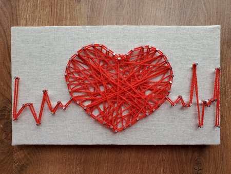 Elaborate string art design of a heart intertwined with heartbeat line creates unique and captivating visual.の写真素材