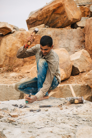 Hampi, India - March 1, 2016: Mining workers manually excavating stone with hammer in Karnataka state of India. Daily life of indian craftsmanのeditorial素材