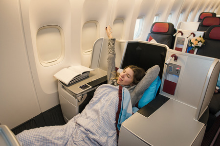 Woman passenger relaxing at the business class of airplane in comfortable single seat. Flight at first class planeの写真素材