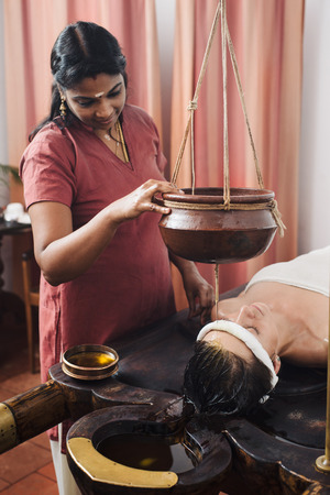 Caucasian woman having Ayurveda shirodhara treatment in India, Kerala stateの写真素材