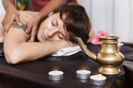 Caucasian woman having Ayurveda treatment in India. Kerala. Oil body massage, Asian spa accessories and candles .の写真素材