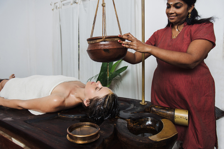 Caucasian woman having Ayurveda shirodhara treatment in India, Kerala stateの写真素材