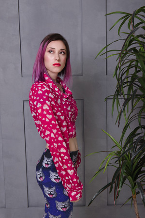 Relaxed sexy young woman looking confused. Stylish girl with pink hair and red lips over gray wallの写真素材