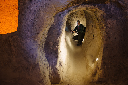 man with lights exploring caves in Derinkuyu ancient multi-level underground city, in Nevsehir Province, Cappadocia, Turkey. Interior of rocky room.の写真素材