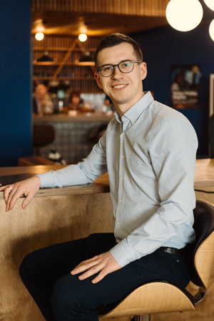Businessman in glasses at the office sitting at high chair. Happy manager smiling