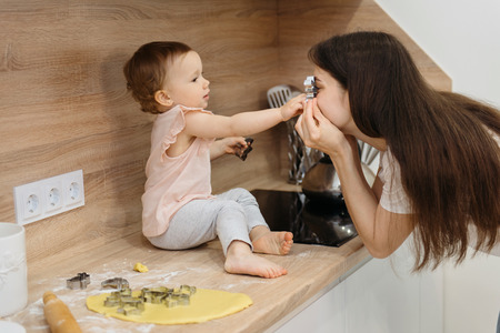 happy family having fun on the kitchen. mother and child daughter preparing the dough, bake cookiesの写真素材