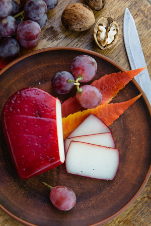 Craft organic aged cheese in herbs with grape, handcrafted gouda cheese, appetizer for romantic...