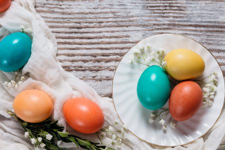 Colored Easter eggs on white plate on wooden gray background, frame for text, copy space, greeting...