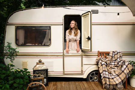 Camping and travelling . Happy person relaxing outdoors near trailer. Woman is ready for road tripの写真素材