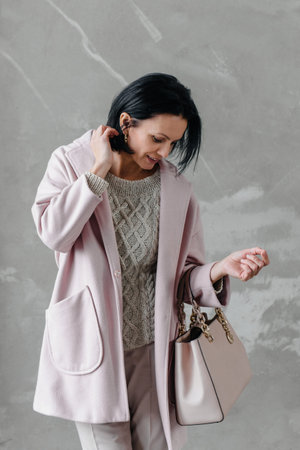 Stylish woman outdoors over the brick wall. Portrait of adult stylish model in her 40s,