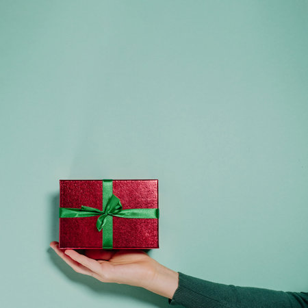 Present on the hand over the plain background. Minimalistic Christmass or Valentine gist concept...
