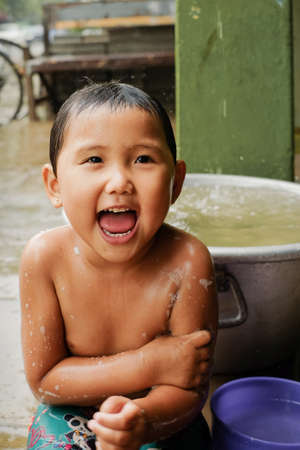 Bagan, Myanmar: May, 25, 2016. Child washing under the rain on the street of Bagan. Happy pour Asian unknown boy in Burma. Myanmarのeditorial素材