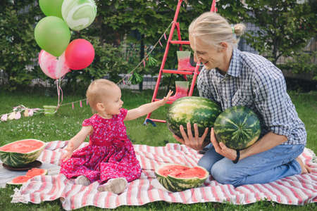 Father and child on a picnic eating big watermelons. Summer family party outdoors with toddler daughterの写真素材