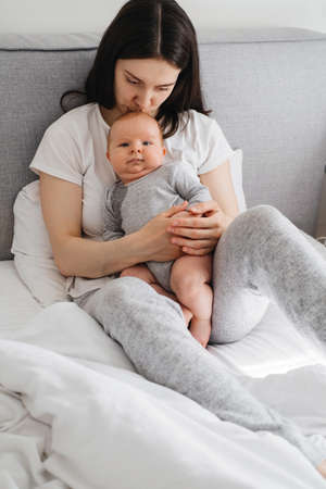 Breast feeding mom at home. Baby sitting on mothers hands, Cuddle a baby and talking to cute infantsonの写真素材