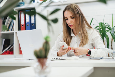 Tired businesswoman using laptop and smartphone for communication and work on-line in modern...